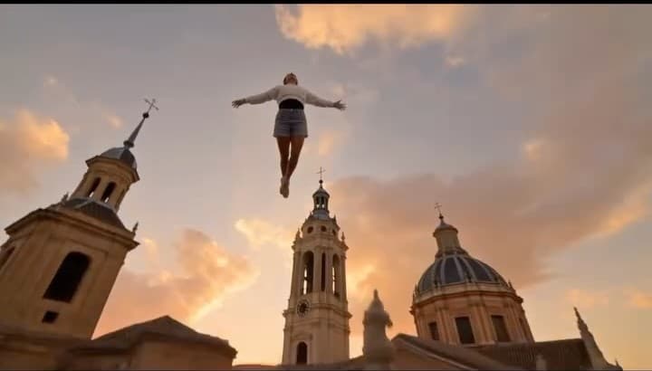The final frame ~ a small figure suspended above Madrid church domes and bell towers at golden hour