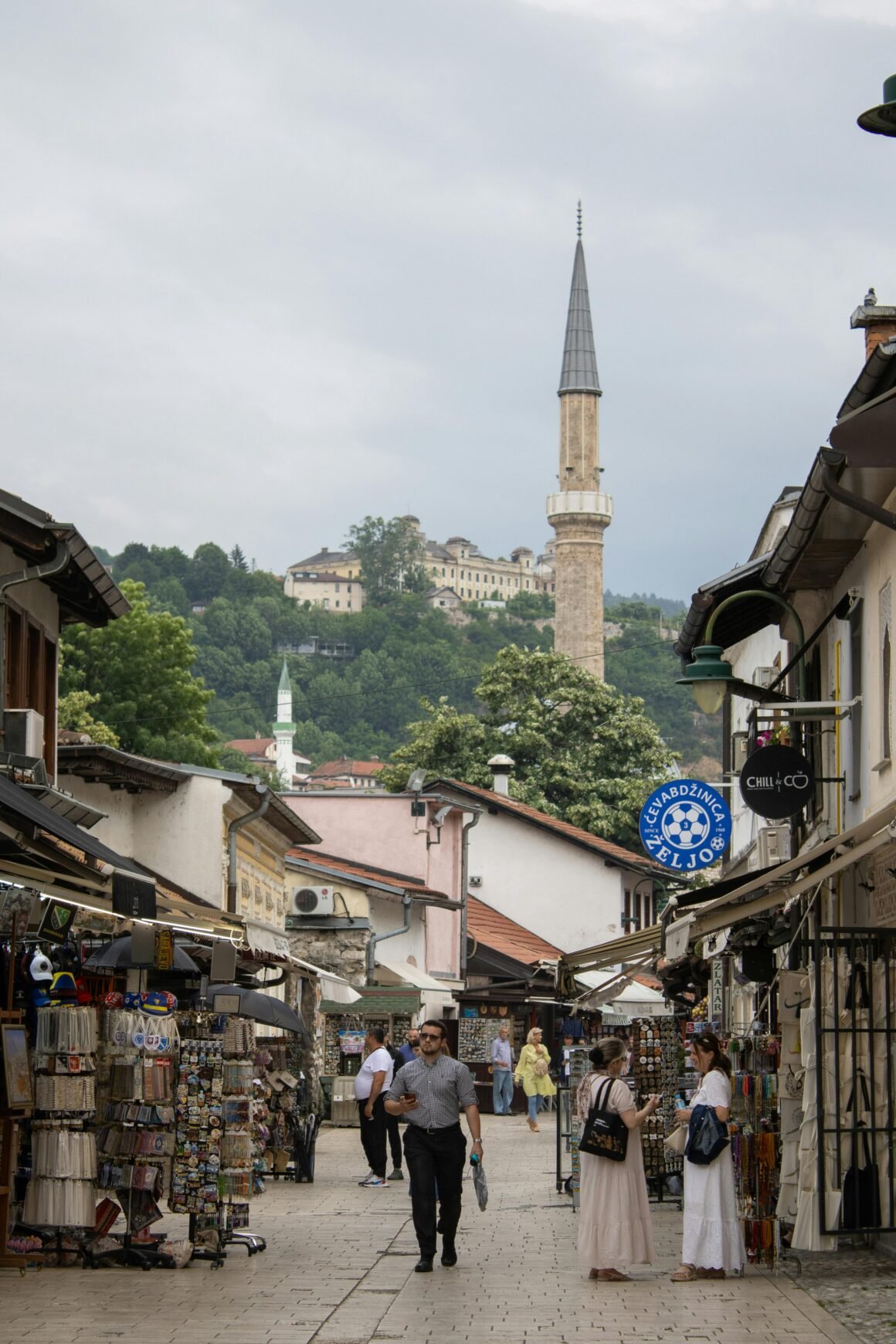 Explore the vibrant market street in Sarajevo with a view of the historic minaret in the background.